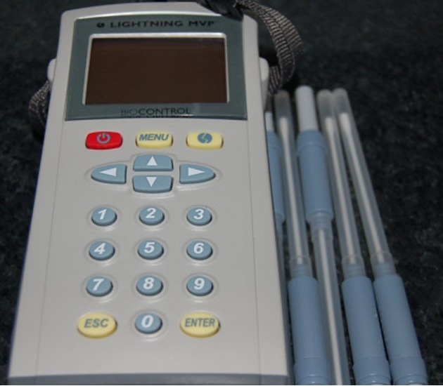 A grey machine with a blue key pad, and blue plastic swab cases next to it.